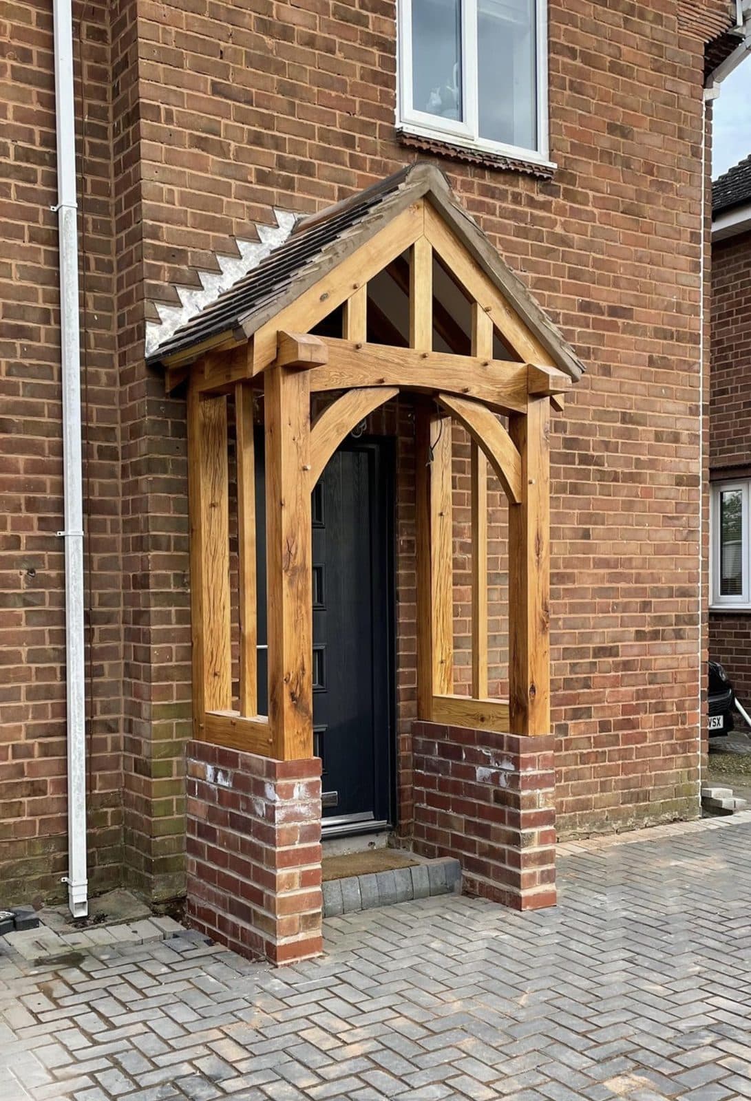 The Broadway oak porch on a brick house, curved braces under the gable and oak side screens on brick dwarf walls