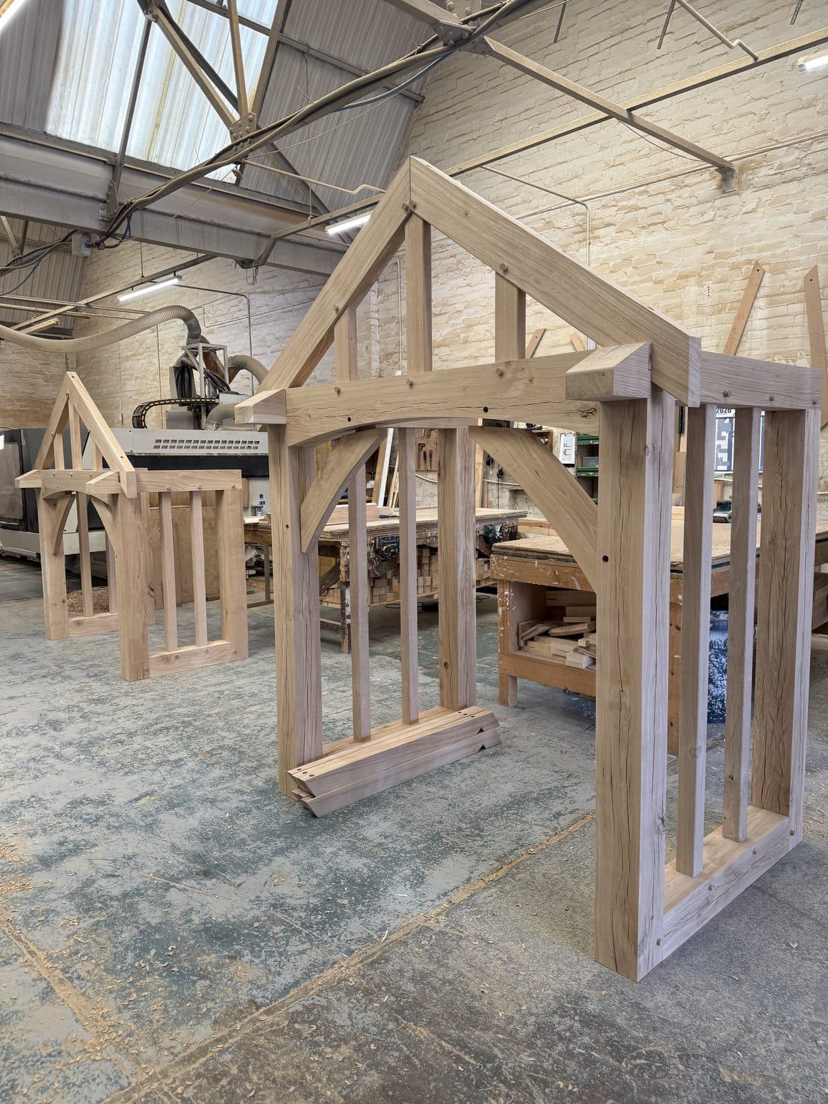 Two oak porch frames standing side by side in the workshop, dry-fitted before being numbered and packed